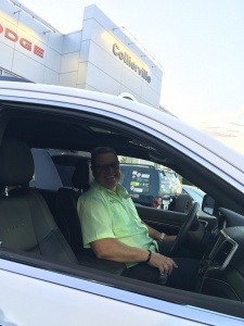 Smiling man sitting in a white car.