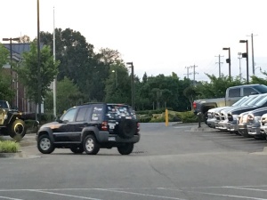 Black Jeep with many stickers parked in lot.