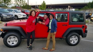 Red Jeep with three people smiling.