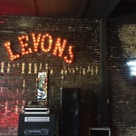 Brick wall with neon Levon's sign.