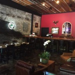 Brick wall bar with wooden tables and chairs.