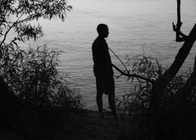 Silhouette of a man standing by a lake.