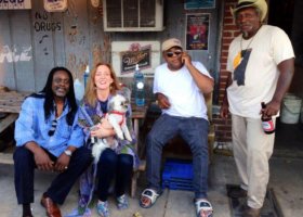 Four people, a dog, and a beer outside a bar.