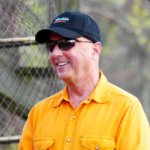 Smiling man wearing a yellow shirt and sunglasses.