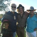 Four men wearing hats, smiling for photo.