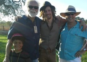 Four men wearing hats, smiling for photo.