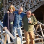 Three friends smiling on wooden stairs.