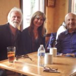 Three people sitting at a table in a cafe.