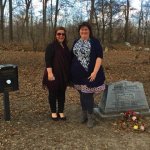 Two women standing by a grave.