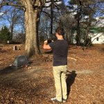 Man taking photo of tombstone in cemetery.