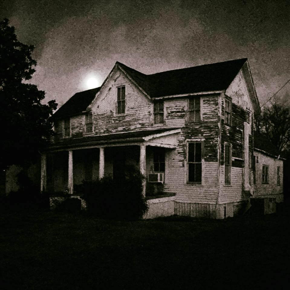 A weathered farmhouse under a full moon.