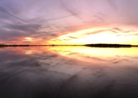 Sunset reflected in calm lake water.