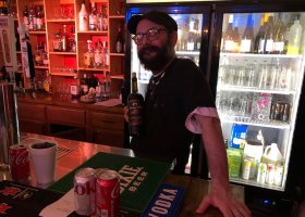 Man at bar holding a bottle of wine.