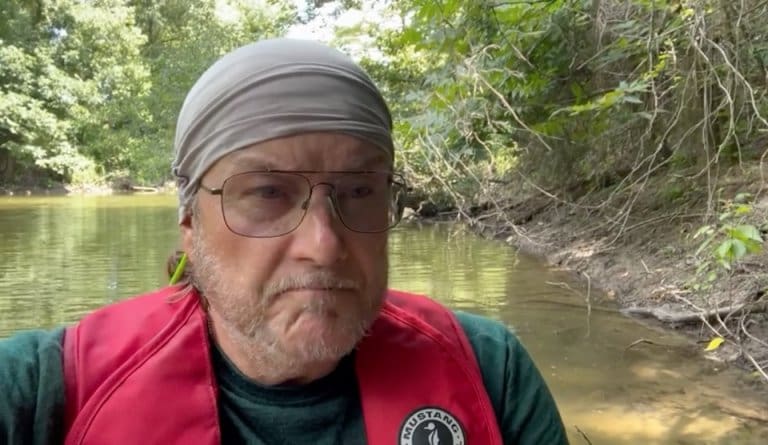 Person in bandana near riverbank