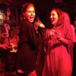Two women dancing in a dark club.