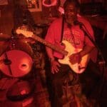 Man plays electric guitar in a bar.