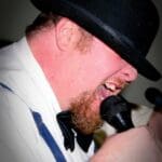 Man in a hat singing into a microphone.