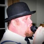 Man in a bowler hat singing into a microphone.