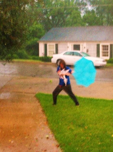 Person holding blue umbrella in rainstorm