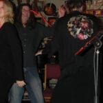 Three people singing karaoke at a bar.