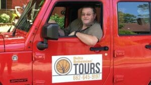 A man in a red Jeep with Delta Bohemian Tours logo.