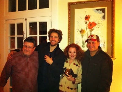 Four people gathered by a framed painting