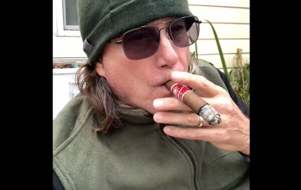 Individual with sunglasses enjoying a cigar