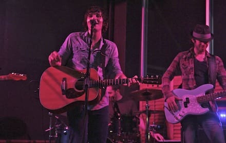 Musician singing and playing guitar on stage