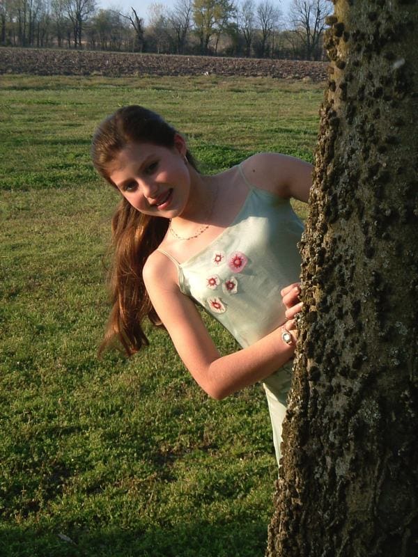 Girl peeking from behind a tree