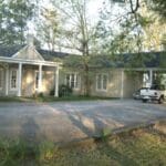 A white house with a porch and a truck in the driveway.