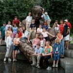 Group of students posing with a statue.