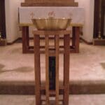 Baptismal font on wooden stand in church.