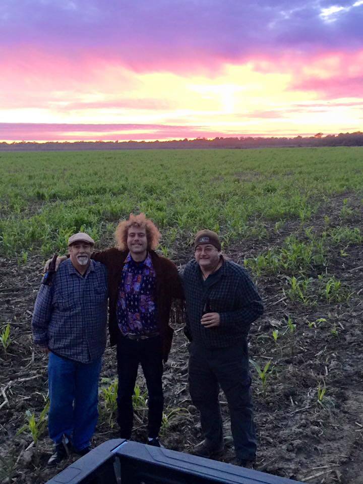 Friends standing in a lush green field.