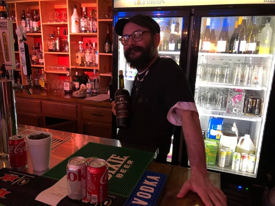 Bartender holding a bottle behind bar