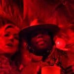 Two people, one wearing a hat, red light