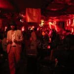 Man in suit in dimly lit bar with crowd.