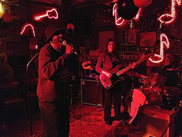 Musicians playing under red neon lights