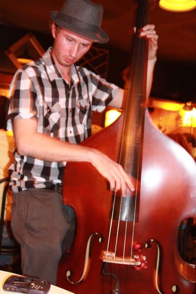 Person in hat playing upright bass instrument