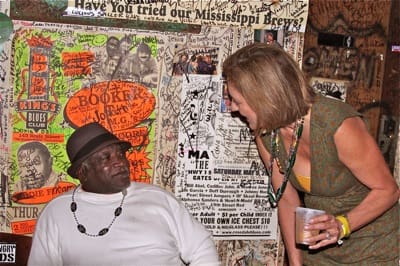 Woman holding drink, talking to seated man