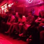 Group of people sitting in a red-lit room.