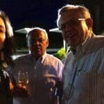 Three people smiling for a photo at night.