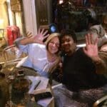 Two women laughing over drinks at a cafe.