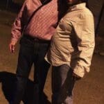 Two men smiling and standing together.
