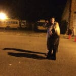 Two people stand near parked school buses.