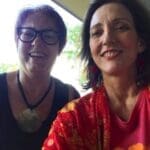 Two women smiling, one wearing glasses.