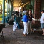 People gather on porch with dog and chairs.