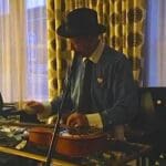 Man in hat playing a pedal steel guitar.