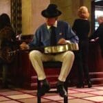 Man in a hat playing a guitar with a band.