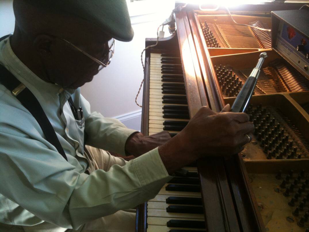 Piano technician at work on keys