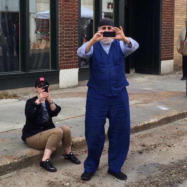 Woman photographing man on urban street